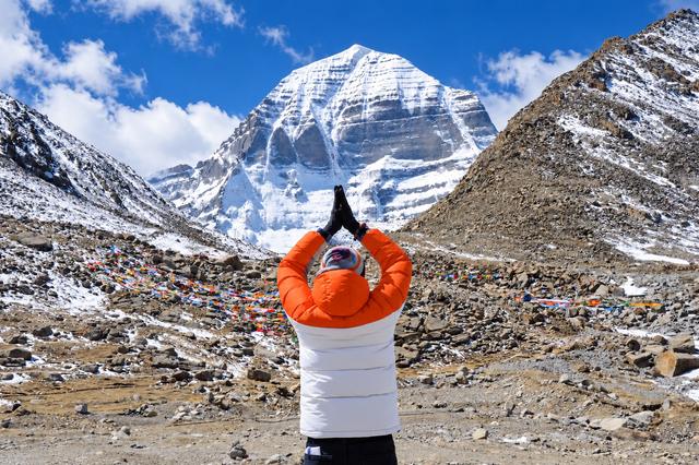 A pilgrim with folded hands facing Mount Kailash