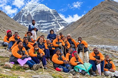 Coral Yatra pilgrims in orange jackets seated below Mount Kailash